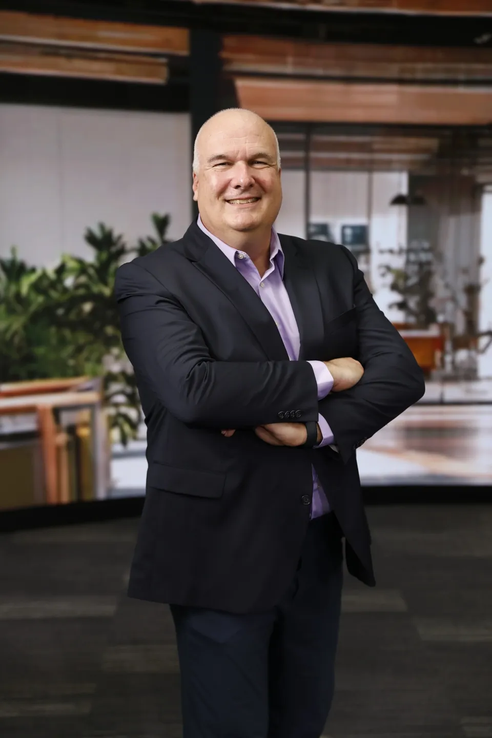 Confident businessman standing with arms crossed in an office.